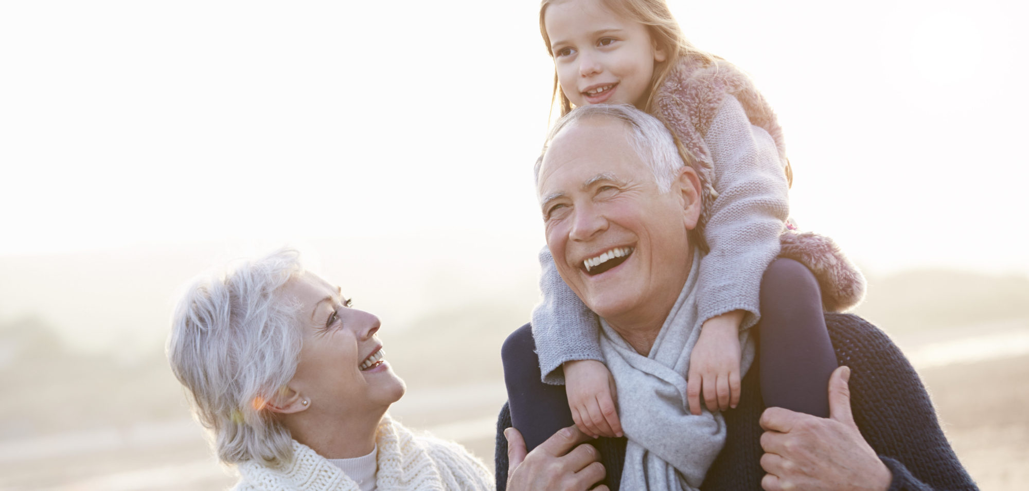 Grandparents And Granddaughter Walking On Winter Beach